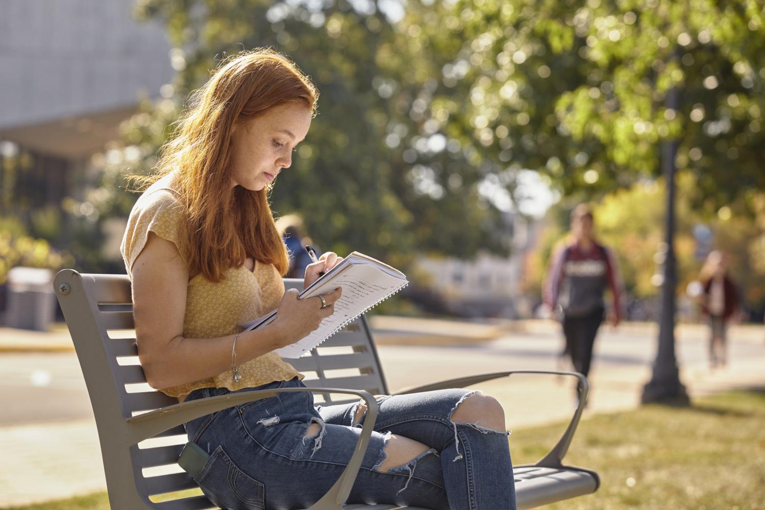 A <a href='http://atvc.braendebriketter.com'>全球十大赌钱排行app</a> student reads on a bench along Campus Drive.